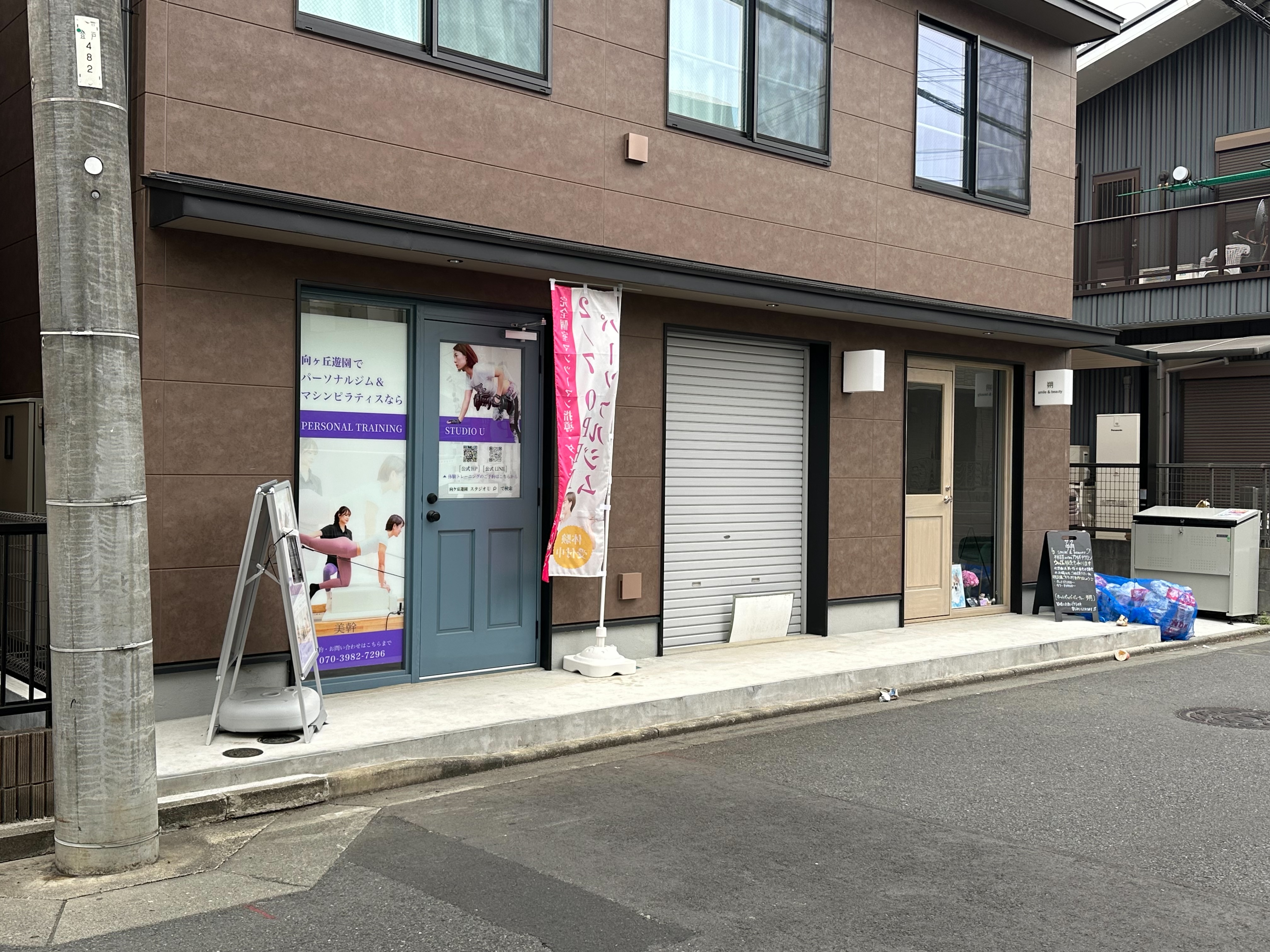 まっすぐ進むと、左手に茶色い建物が見えます。その建物の一番左にある青い扉が当スタジオの入り口です