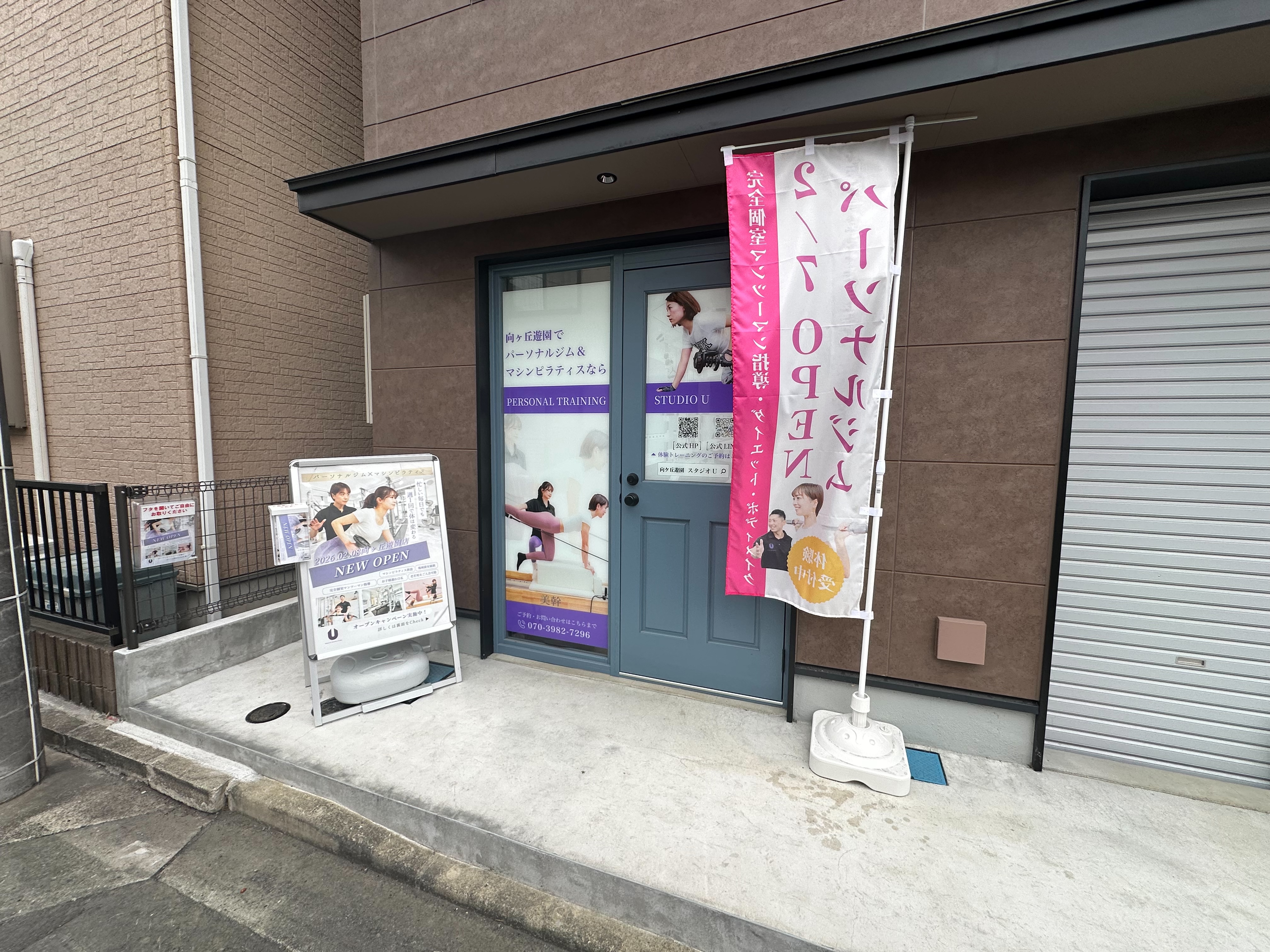 まっすぐ進むと、左手に茶色い建物が見えます。その建物の一番左にある青い扉が当スタジオの入り口です